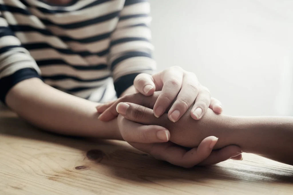 image of two people holding hands, listening with care and empathy.